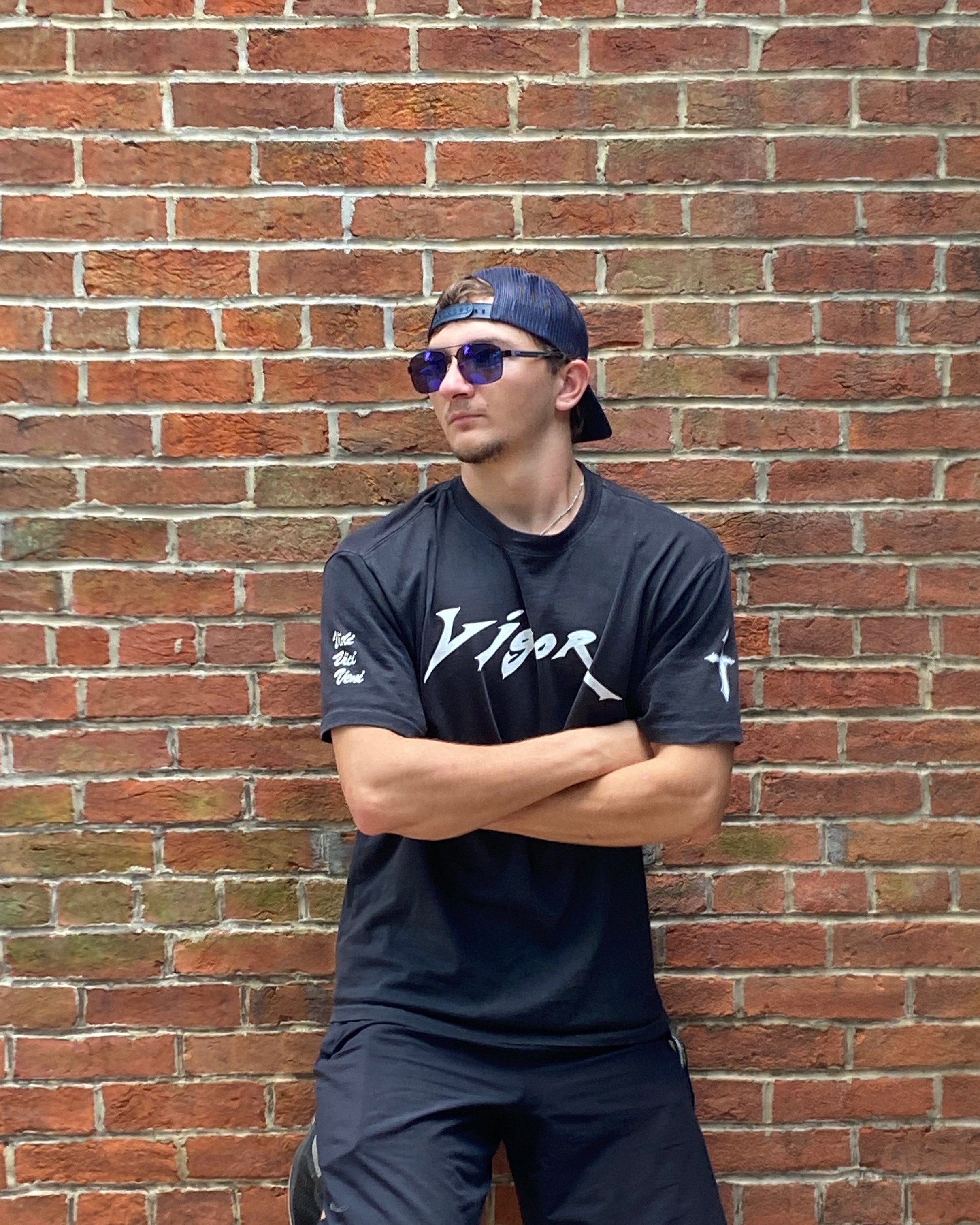 Person wearing a black t-shirt and shorts on a brick pavement