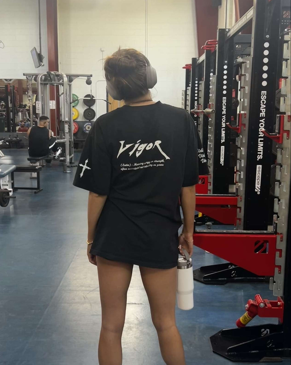 Person wearing a black t-shirt with 'Vigor' branding in a gym setting.